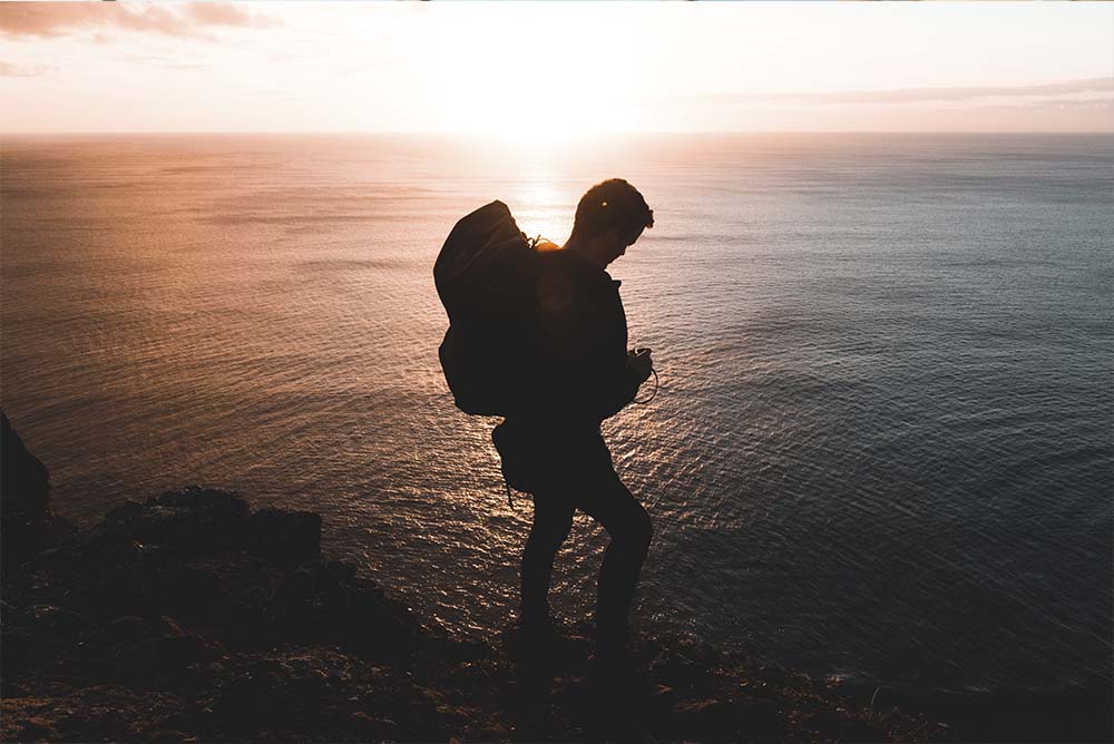 Um homem com mochila nas costas vagando próximo ao mar, representando a quebra da Rotina de advogado