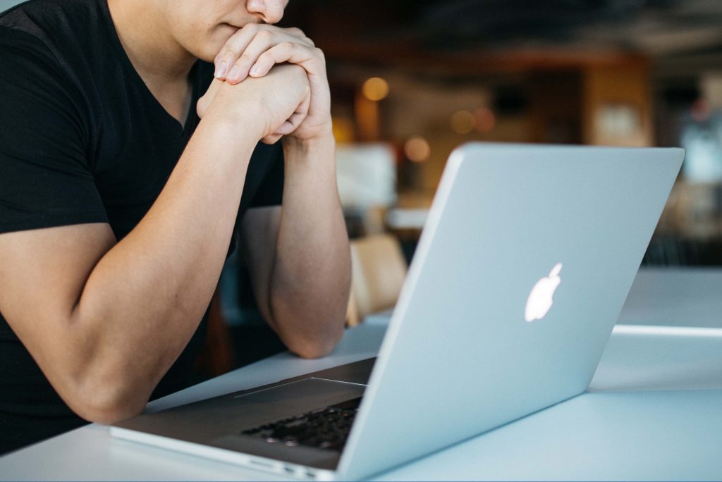 Advogado mexendo em notebook sobre uma mesa com semblante de preocupação. Imagem representa inseguranças sobre Gestão de escritórios de advocacia à distância