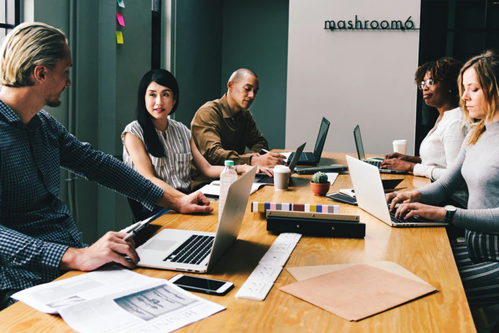 Diversas pessoas ao redor de uma mesa de reunião conversando. Representa a criação de estruturas para web service