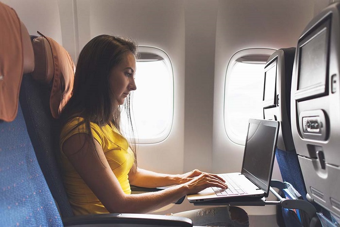 mulher sentada em um avião usando um laptop - trabalho remoto na advocacia