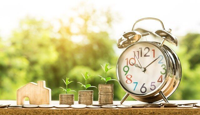 Evoluir as finanças do escritório de advocacia - foto de um relógio ao lado de pilhas de moedas de diferentes tamanhos